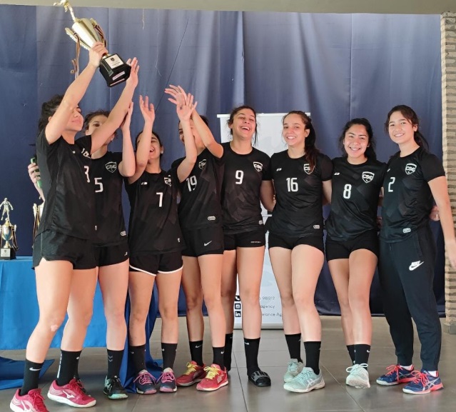 jóvenes mujeres del colegio santa elena levantando trofeo por campeonato de handball